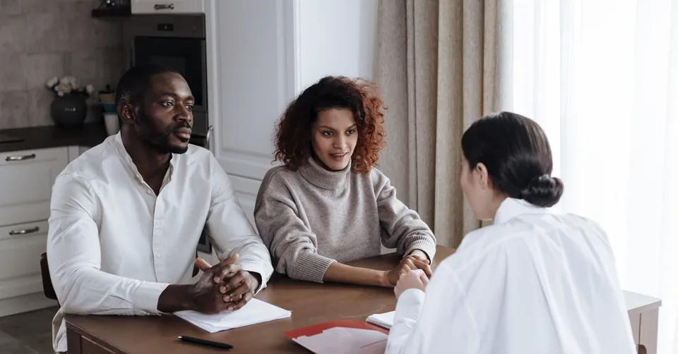 Un couple échange autour de documents avec une professionnelle de l’accompagnement